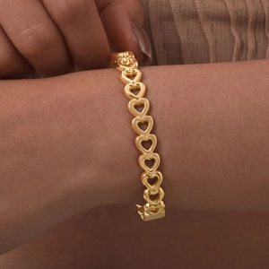 Close-up of a gold hollow heart bangle on a model wrist showing fine metal craftsmanship