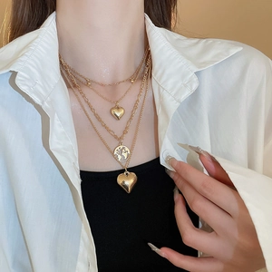 Layered gold heart and globe map necklace set with shiny metallic finish on female model