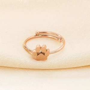 Detail of rose gold cat paw ring with open design on elegant silk fabric background
