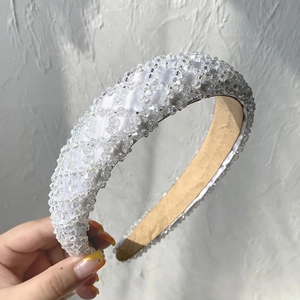 Detail of white satin headband adorned with clear crystal beads and faux pearls