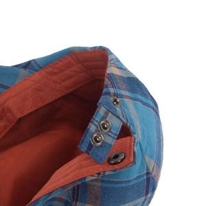 Blue plaid newsboy cap with orange lining showing adjustable silver metal snap buttons