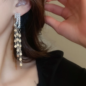 Close-up of long silver tassel earrings with zircon studs and dangling sequins