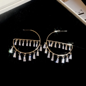 Macro detail of gold earrings with cubic zirconia fringes on black velvet backdrop