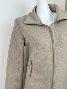Detail of oat-colored slim-fit zip-up sweater with high collar and fine knit texture
