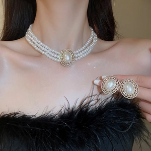 Detail view of French vintage faux pearl necklace and earrings set with gold rhinestone accents