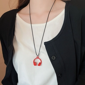 Close-up of a red headphone pendant necklace worn by a model over black and white clothing
