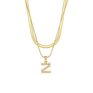 Detail of gold double-layer chain necklace featuring letter Z pendant and white pearls