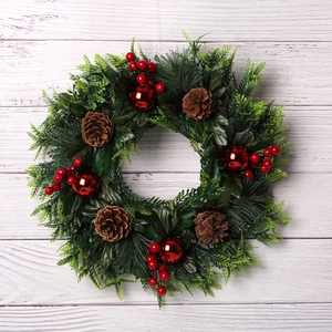 Couronne de Noël avec baies rouges, pommes de pin et boules sur fond bois blanc