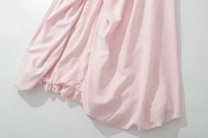 Detail of pink chiffon dress showing smooth fabric texture and ruffle hemline finish