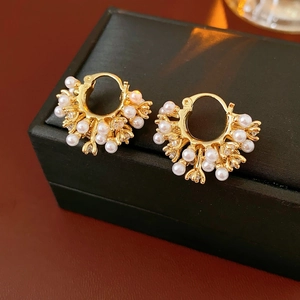 Close-up of vintage gold U-shaped earrings with pearls and zircon on a jewelry box