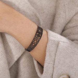 Black stainless steel open cuff bracelet with intricate hollow Celtic knot design on wrist