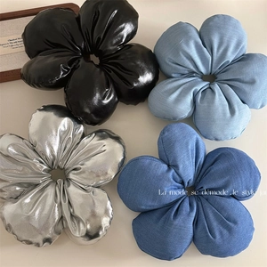 Oversized flower hair ties in black leather, silver metallic, and blue denim fabric