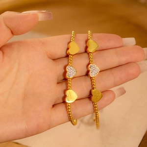 Elegantes goldenes Schlangenkettenarmband mit funkelnden Herzanhängern und Perlendetails