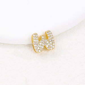 Macro shot of gold letter W pendant encrusted with sparkling cubic zirconia crystals