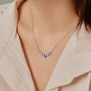 Detail of S925 silver necklace featuring blue and pink gemstone heart pendant on model