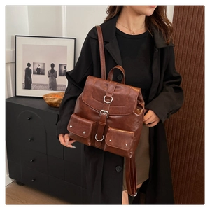 Détail d'un sac à dos vintage marron avec boucles métalliques et poches multiples