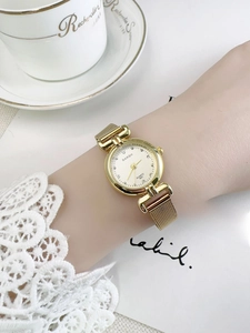 Close-up of gold vintage quartz watch with rhinestone scale and Milanese mesh strap