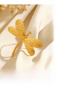 Close-up of golden dragonfly accessory with textured wings on white satin background