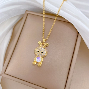 Detailed view of gold rabbit pendant with zircon and opal stones on white silk