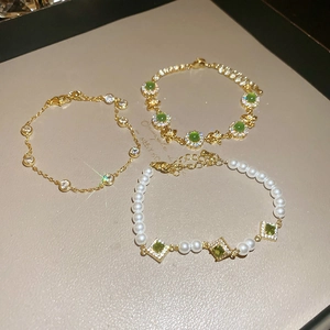 Detailed close-up of three gold-plated bracelets featuring green zircon and pearls