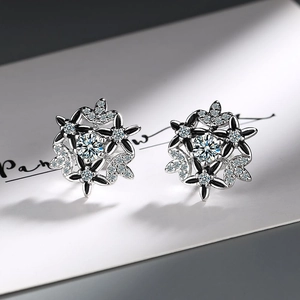 Macro shot of silver snowflake earrings with black enamel and sparkling white zircon studs