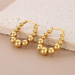 Elegant gold U-shaped geometric hoop earrings with polished gradient beads on marble