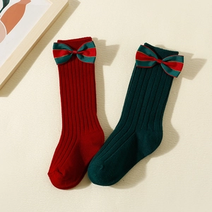 Christmas baby socks with red and green rib knitting and decorative festive bows