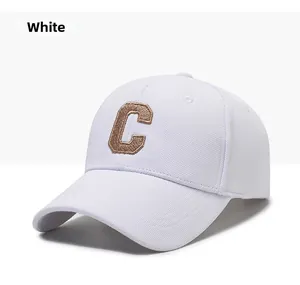 Detailed close-up of white cotton baseball cap featuring golden letter C embroidery