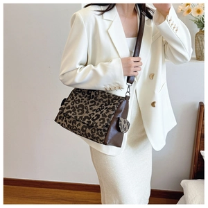 Detail of leopard print tote featuring brown leather strap and patchwork stitching