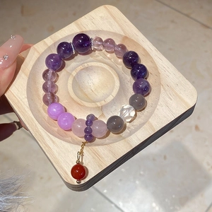Detail of multi-gemstone bead bracelet with amethyst and red agate ball pendant