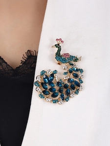Peacock brooch with colorful crystals pinned on white blazer lapel for elegant styling