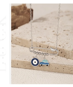 Detailed view of silver paperclip necklace with evil eye and blue car charms on stone