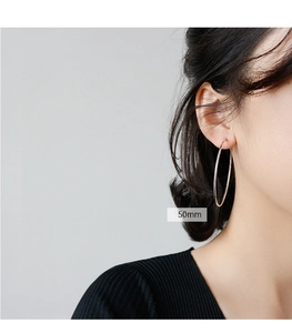 Model wearing 50mm sterling silver large hoop earring with minimalist polished finish