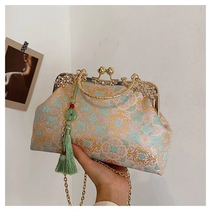 Detailed embroidery on brocade handbag featuring peacock clasp and green silk tassel