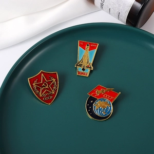Detailed macro view of three vintage Soviet enamel pins on an elegant green ceramic plate
