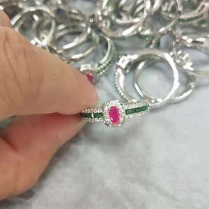 Macro shot of vintage silver ring featuring an oval red center stone and emerald green side stones