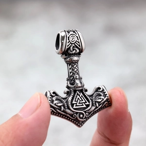 Silver stainless steel Viking Mjolnir pendant with Valknut symbol held by hand