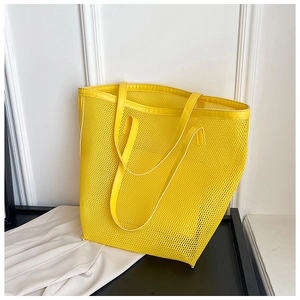 Detailed close-up of a bright yellow mesh beach tote bag with white piping and sturdy handles