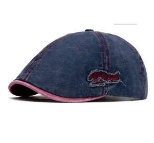 Detail of navy flat cap with red contrast stitching and embroidered Natural patch