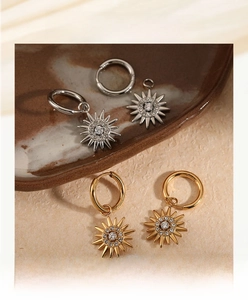 Detail of sunburst hoop earrings in gold and silver with clear cubic zirconia stones