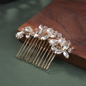 Close-up of golden bridal hair comb with glittering crystals on dark green surface