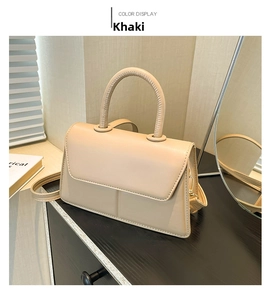 Detail of khaki leather handbag featuring a smooth finish and curved top handle
