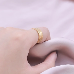 Gros plan d'une bague en acier doré avec motif d'étoiles sur un fond en soie douce