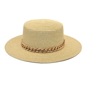 Détail du chapeau de paille beige style canotier avec une chaîne dorée décorative