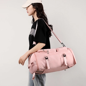Pink sports gym bag with wet dry separation and adjustable shoulder strap worn by model
