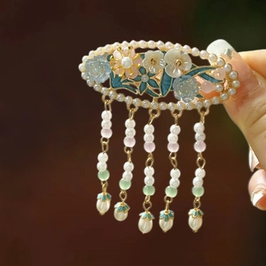 Detailed macro of vintage enamel flower hair clip with pearls and long hanging tassels