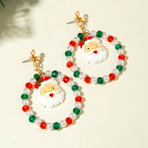 Close-up of Christmas beaded wreath earrings with resin Santa Claus pendant and bow