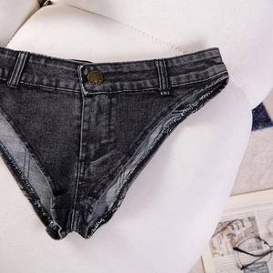 Dettaglio di mini shorts in denim grigio scuro elasticizzato con bordi sfilacciati su felpa