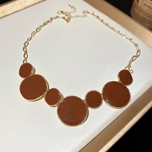 Collier vintage doré avec 7 pendentifs ronds en émail marron sur présentoir