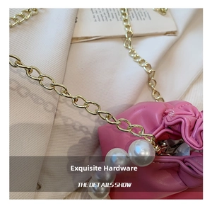 Detail shot of a pink pleated bucket bag featuring elegant gold chain and large pearl charms